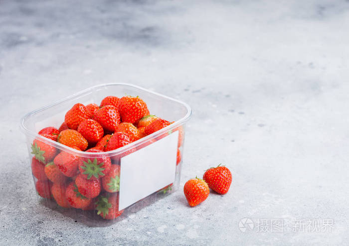 塑料托盘容器的新鲜有机健康草莓在石厨桌背景.
