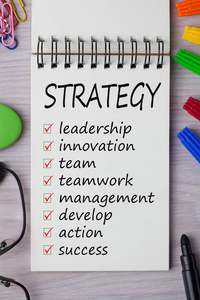 策略与关键字写在笔记本和办公用品。 商业概念。