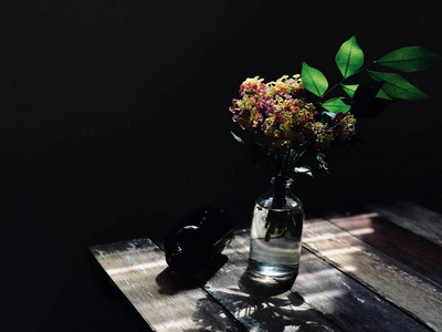 美丽的鲜花，玻璃瓶里有绿叶，棕色的空瓶子放在乡村的木桌上