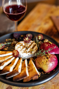 烤卡蒙伯与烤苹果和葡萄与面包片在一个黑色的盘子上，木制背景，乡村风格。 餐厅