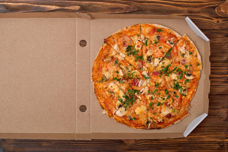 美味的意大利披萨放在木桌上的盒子里。送披萨。俯视图。 复制空间。