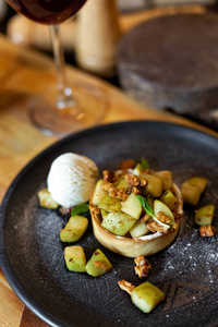 英国苹果碎与坚果薄荷和一勺冰淇淋在一个黑色的盘子上，木制背景，乡村风格。 餐厅
