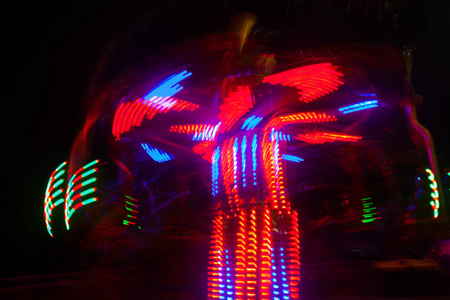 一个模糊的彩色旋转木马在游乐园夜间照明。 Bokeh和长时间暴露的影响