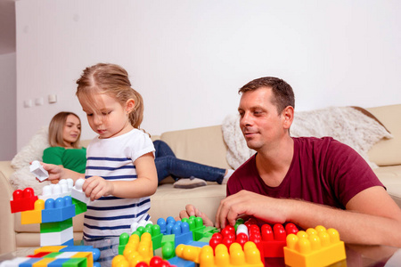 微笑的父亲和可爱的女儿在家一起玩立方体