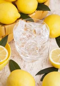 一杯有机的新鲜柠檬，还有夏季的水，在浅木色的背景下加入生柠檬