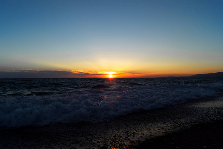 晚上的海景。 夕阳在水中倒影。 有沙子的海岸线。