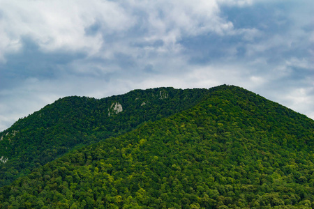 夏天的山景。 有绿色树木的山。 天空中戏剧性的云彩。