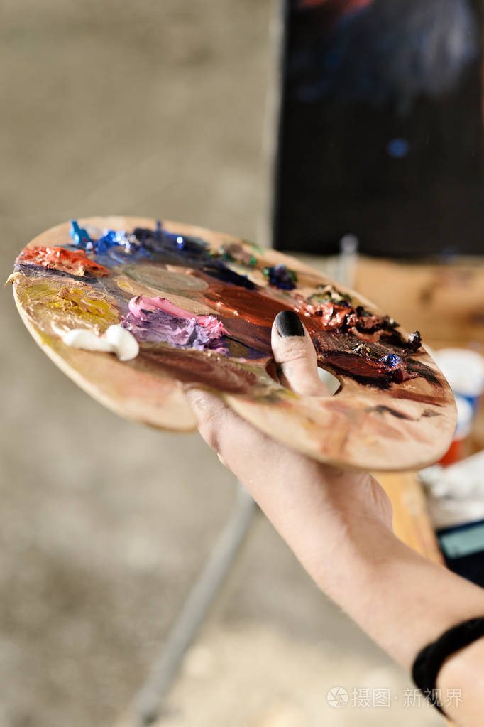 调色板与颜色在一个女孩手中的红色衬衫在一个笼子美术的概念