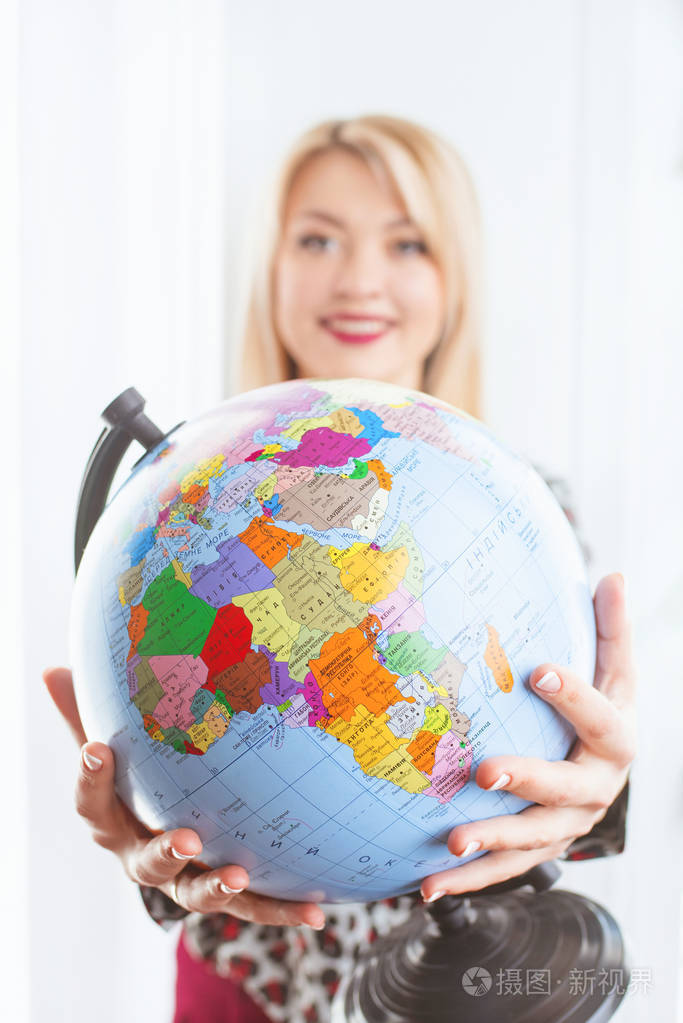 美丽开朗微笑的金发女旅行社手里拿着地球仪