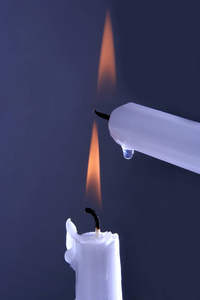 两支在蓝色背景上燃烧的白蜡烛