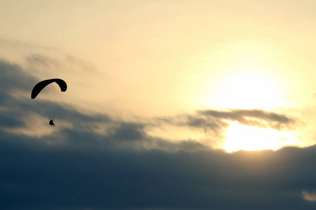 滑翔伞在天空中迎着夕阳飞翔