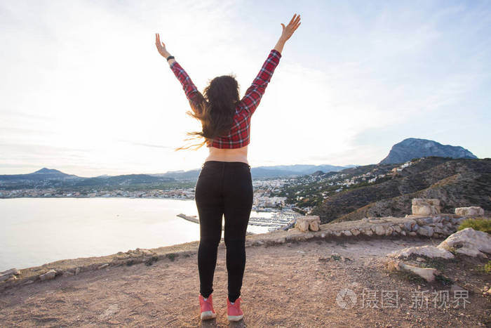 自由和旅行的概念--站在悬崖边, 用举起的手望着