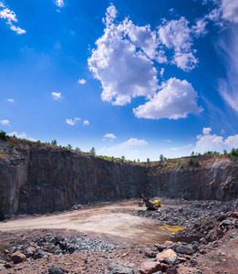 一台大型履带式挖掘机在采石场露天开采花岗岩石料。 加工生产石料和砾石。 采石场采矿设备。