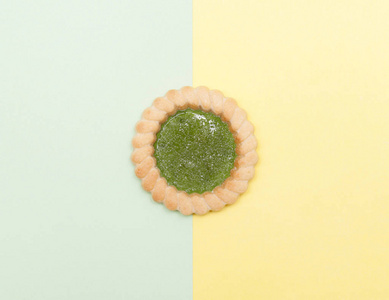 绿色和黄色背景上的微型饼干。 食物和甜点的最小概念。 平躺顶部视图。