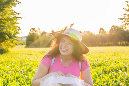 夏天和自然的概念健康的微笑的年轻女子躺在绿草如茵与野花。她又笑又高兴