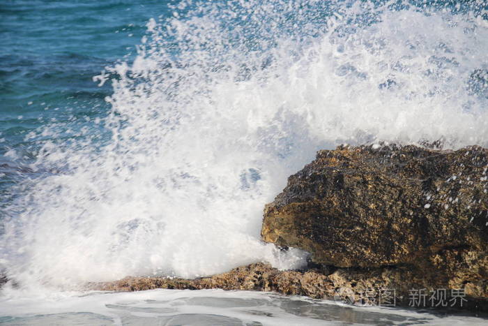 海浪拍打在岸边的一块大石头上,白色的飞溅,清澈的大海,海上度假