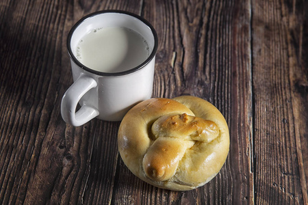 粗鲁的风格。黄油面包和一杯牛奶放在木桌上。