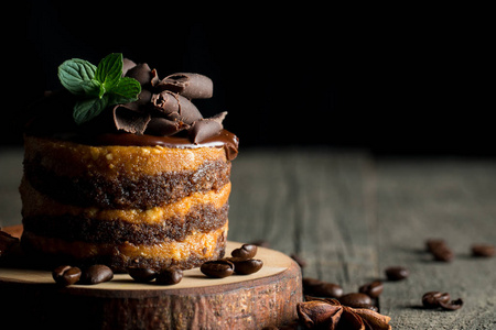 黑色石板上的巧克力蛋糕，黑色背景特写照片上的薄荷咖啡豆。 新鲜美味的甜点食品概念。