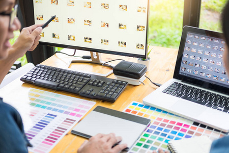在繁忙的创意办公室，平面设计师团队使用色板进行网页设计，使用平板电脑和触控笔编辑艺术品
