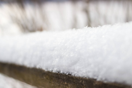 在冬天，毛茸茸的雪在阳光下闪闪发光。 雪躺在背景的木栅栏上，是一个美丽的船。 雪花靠近