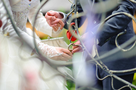 新婚夫妇把象征永恒爱情的锁挂在婚礼上。 结婚传统。