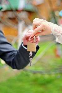 新娘和新郎的手拿着钥匙保管金锁。 新婚夫妇把象征永恒爱情的锁挂在婚礼上。 结婚传统。
