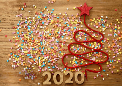 圣诞树从许多彩色纸屑花边和红星玩具上的旧复古风格木制纹理。 新年快乐2020卡