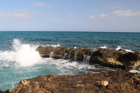 海浪拍打在岸边的一块大石头上，白色的飞溅，清澈的海上度假