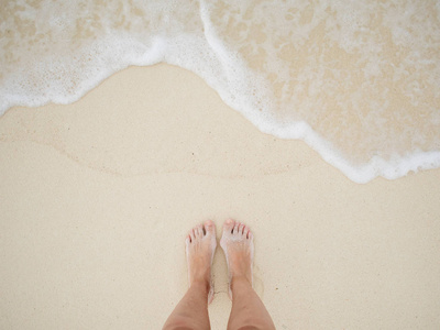 脚在沙子和海泡沫。冲浪