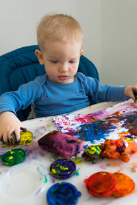 孩子男孩画与手指油漆在纸在孩子桌上