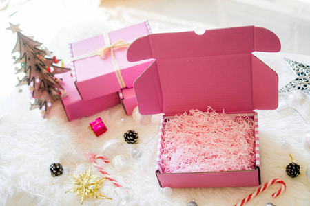 粉色礼品盒打开蝴蝶结带，白色地毯上有明亮的灯糖果和星星