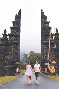 年轻的蜜月夫妇在一个大巴厘岛大门的背景。巴厘岛, 印度尼西亚
