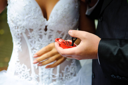 新娘和新郎的手把红锁保持在心脏的形式。 新婚夫妇把象征永恒爱情的锁挂在婚礼上。 结婚传统。