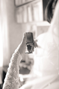 新娘的早晨准备。 那个女孩看着窗户附近的镜子。