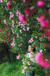 一个穿着日常服装的女孩在一棵开花灌木丛中的肖像