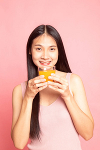 年轻的亚洲女人喝橙汁，粉红色背景