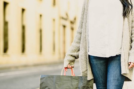 s hand holding shopping bags, with fashionable clothes.