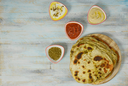 传统的印度Naan面包在木制背景上，有一些沙拉的小盘子LabnehHummus和Matbucha莫罗坎西红柿沙拉，放在顶部