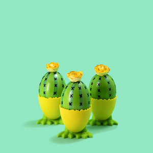 三个有趣的手工仙人掌在鸡蛋做的爪子上。 创意复活节装饰。 最小复活节概念