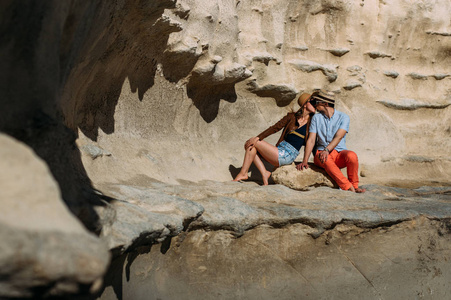 戴墨镜的夫妇坐在海岸线上的石头上接吻，马耳他