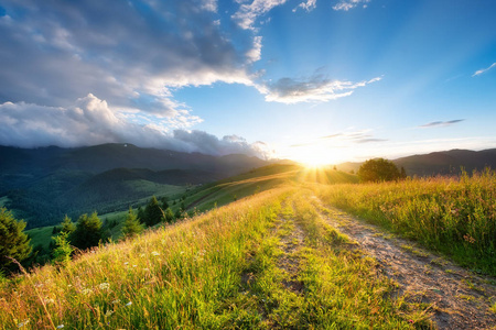 山里的路。 草地和日落。 自然的夏季景观。 太阳照耀着天空。 乡村景观。 山景景观