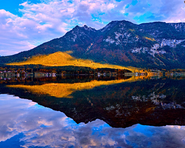 美丽的风景秀丽的日落在奥地利阿尔卑斯山湖。古老的老式乡村房屋和木船房屋在哈尔施塔特山湖的阿尔卑斯山在蓝色的时间。位置 度假村村