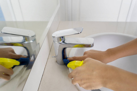 清洁水龙头在卫生间用喷雾清洁剂清洁卫生间的水龙头照片