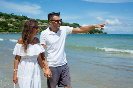 海滩情侣走在浪漫旅行蜜月暑假浪漫。年轻快乐的恋人, 女人和男人牵手拥抱在户外