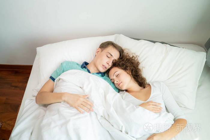 美丽的年轻人和女人喜欢一对夫妇早上在床上拥抱