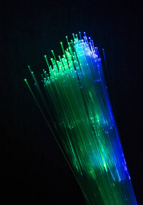 彩色光纤照亮黑暗的背景。 高速互联网概念。 数据传输光纤电缆。 一束许多光纤发光不同的颜色。 技术背景。