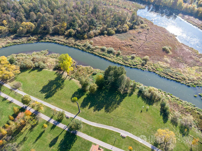 自然景观鸟瞰. 城市公园有茂密的秋树,绿色的草坪,自行车道和河流照片