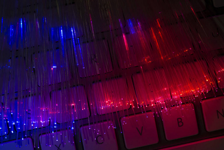 彩色光纤照亮键盘。 高速互联网概念。 数据传输光纤电缆。 一束许多光纤发光不同的颜色。 技术背景。