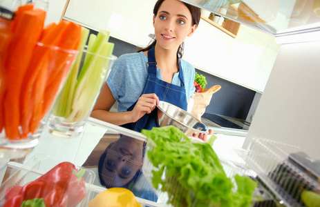 女性站附近打开冰箱充分的健康食品，蔬菜和水果的画像。女性肖像