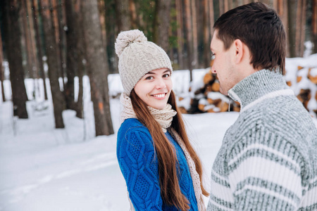 愉快的爱的年轻夫妇走在雪的冬天森林